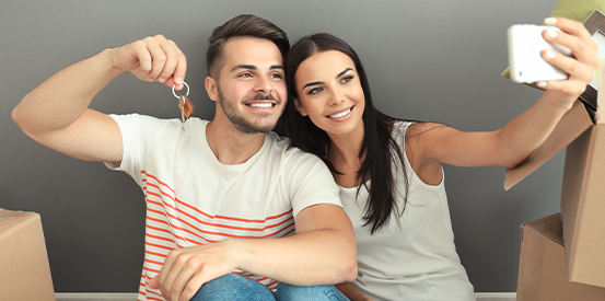 couple taking selfie holding key to their new home