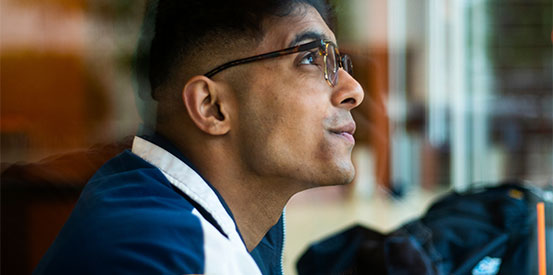 Side profile of a college student who is new to Canada, looking up in deep thought and contemplation.