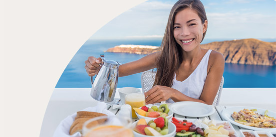 Smiling woman enjoying breakfast with an ocean-view behind her